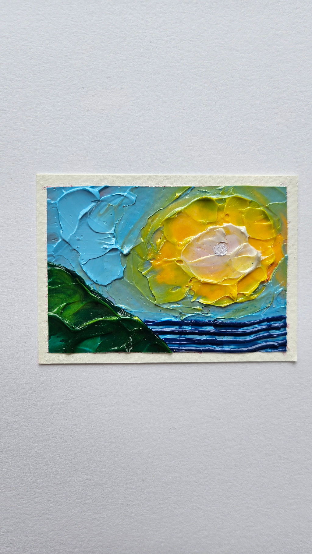 Mini painting of the sun, sea, and hillside