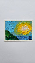 Mini painting of the sun, sea, and hillside