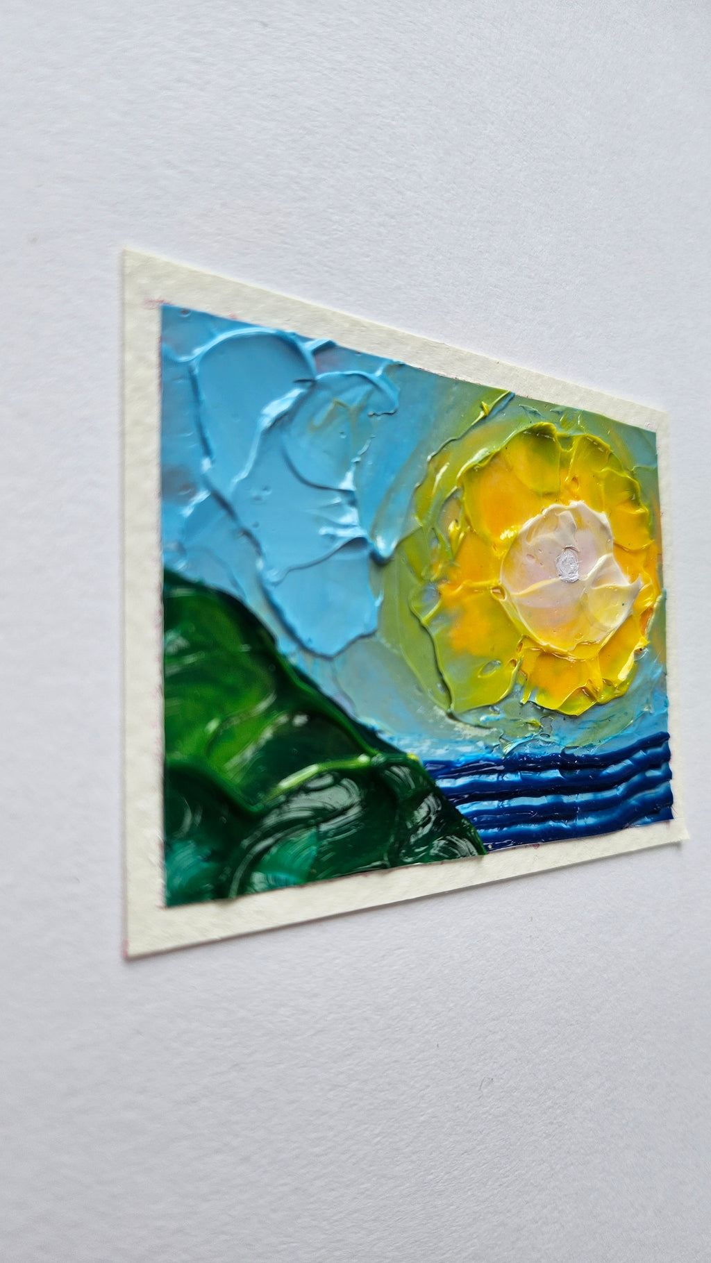 Mini painting of the sun, sea, and hillside