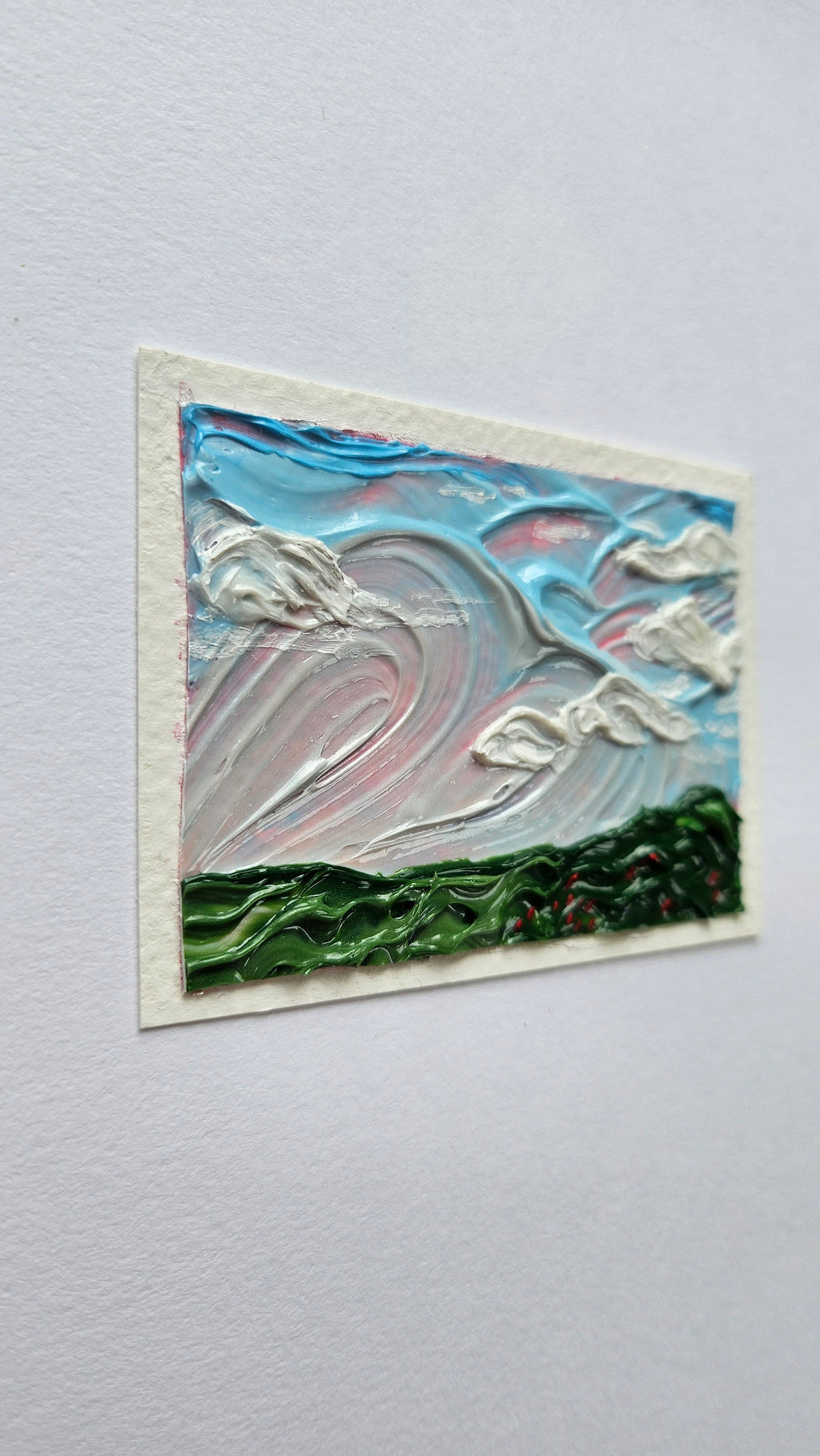 Mini painting of a large clouds and a field of flowers